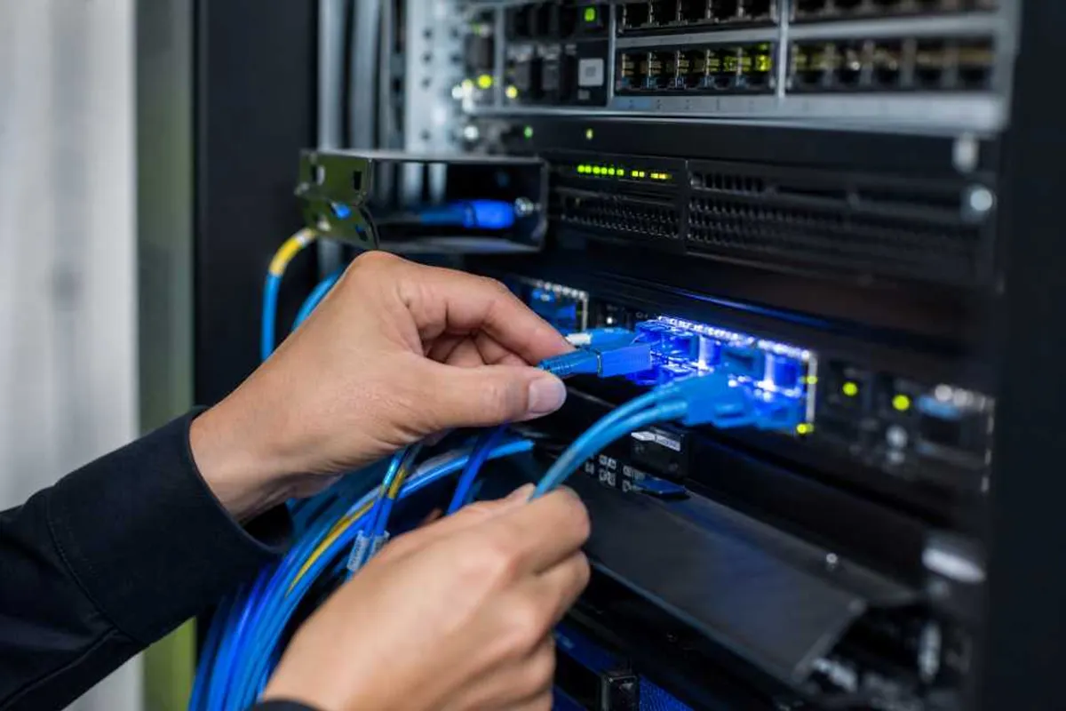 Tecnico instalando cabos de fibra optica em rack de rede empresarial em Bela Vista